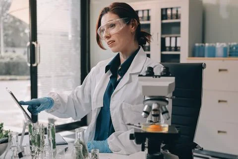 Scientists in lab coats work with plants in a modern lab, focusing on resea.. Stock Photos
