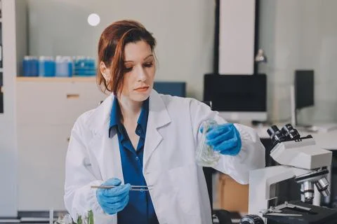 Scientists in lab coats work with plants in a modern lab, focusing on resea.. Stockfoto's