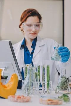 Scientists in lab coats work with plants in a modern lab, focusing on resea.. Stockfoto's