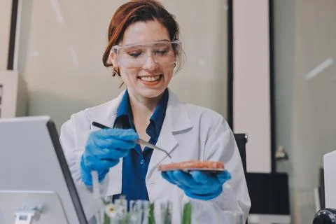 Scientists in lab coats work with plants in a modern lab, focusing on resea.. Stockfoto's