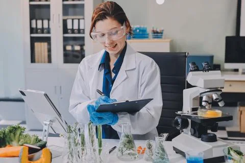 Scientists in lab coats work with plants in a modern lab, focusing on resea.. Stockfoto's