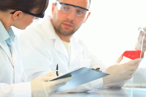 Scientists looking at Erlenmeyer flask and writing results in clipboard NTSC Video stock 5090368