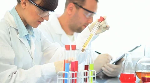 Scientists looking at test tubes and writing results on clipboard HD Stock Footage 5090413