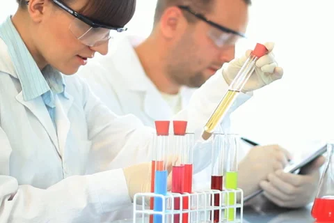 Scientists looking at test tubes and writing results on clipboard NTSC Stock Footage 5090417
