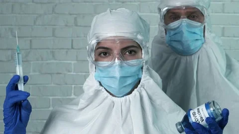 Scientists with protective kit holding a syringe with COVID-19 vaccine Stock Footage 144435442