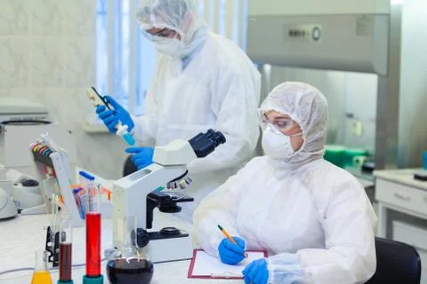 Scientists in protective suits in a science laboratory study a dangerous virus Stock Photos