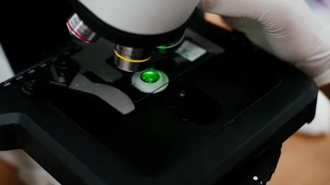 Scientists to rotate the lens of a microscope with slide and green light	 Stock Footage 134273707