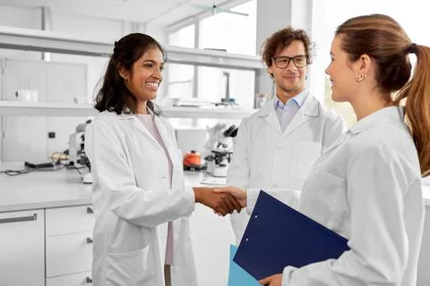 Scientists shaking hands in laboratory Foto stock