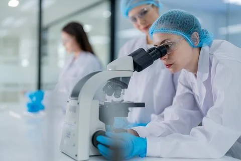 Scientists work in a lab examining samples through a microscope during a re.. Stock Photos