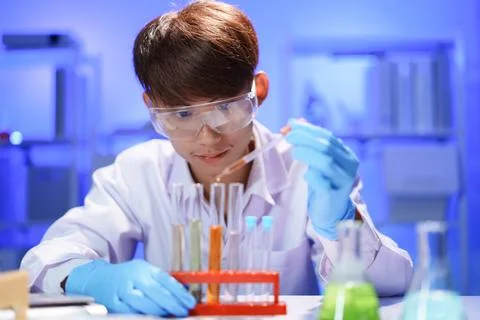 Scientists working in Laboratory using pipette dropping liquid sample into te Stock Photos
