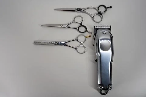 Scissors and a clipper on a white table Stock Photos