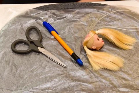 Scissors and homemade tool on the table, how to make hair for a doll, hobby c Stock Photos