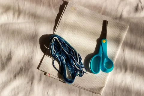 Scissors and multi-colored threads lie on the fabric Stock Photos