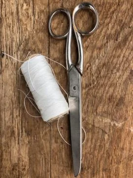 Scissors and spool of thread, rope on a wooden table Foto stock