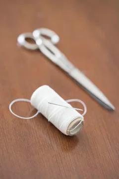 Scissors and spool of white thread on wooden table Stock Photos