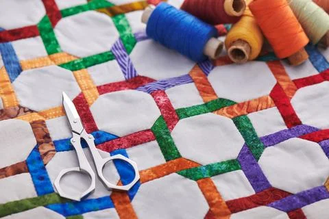 Scissors and spools of thread lying on fragment quilt top sewn by hand from.. Stock-Fotos