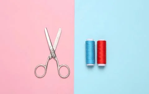 Scissors and spools of thread on pink and blue background Foto stock