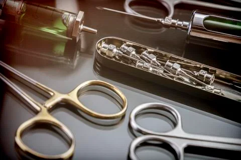 Scissors and syringe in a table of operations of a hospital, conceptual image Stock Photos