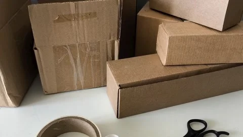 Scissors and tape on the table against the background of boxes. Warehouse Vidéo 330040091