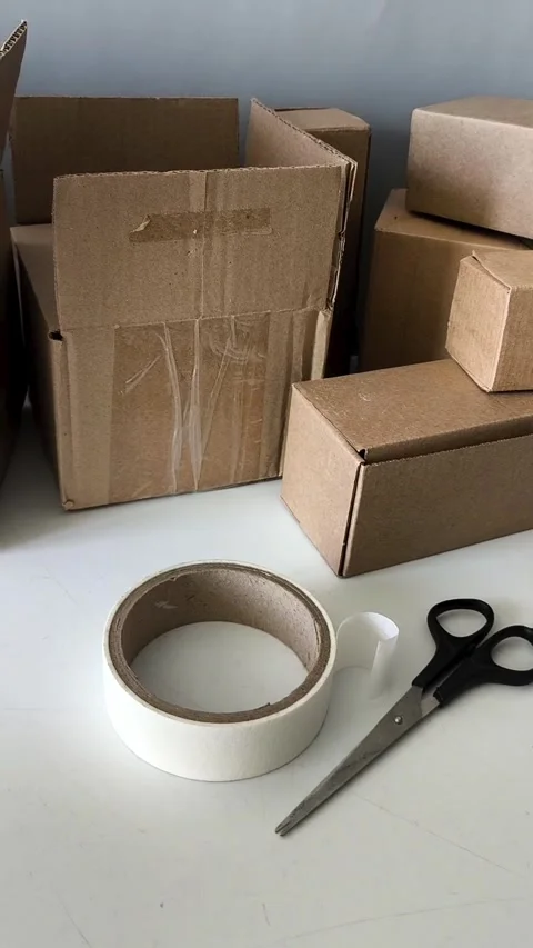 Scissors and tape on the table against the background of boxes. Warehouse 库存影片 330040092