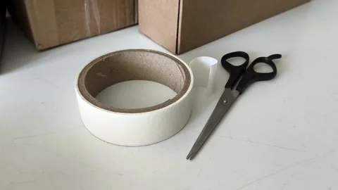 Scissors and tape on the table against the background of boxes. Warehouse 库存影片 330040095