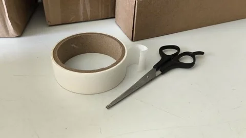 Scissors and tape on the table against the background of boxes. Warehouse Stock-Footage 330040100