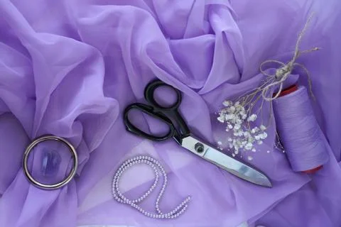 Scissors and thread on a purple silk fabric Foto stock