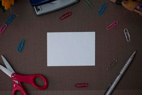 Scissors and writing equipments plus plain sheet above textured backdrop Stock Photos