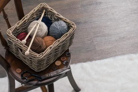 Scissors and yarn inside old basket on wooden chair 스톡 사진