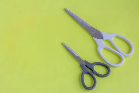Scissors, big scissors and small scissors on a yellow background. White and b Foto stock
