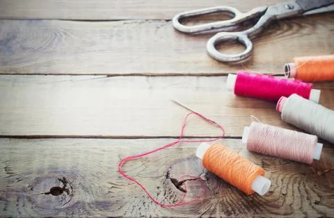Scissors, bobbins with thread and needles. Old sewing tools on the old wooden Stock Photos