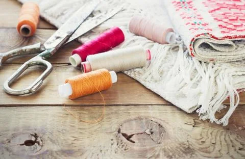 Scissors, bobbins with thread and needles, striped fabric. Old sewing tools o Stock Photos