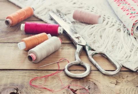 Scissors, bobbins with thread and needles, striped fabric. Old sewing tools o Stock Photos