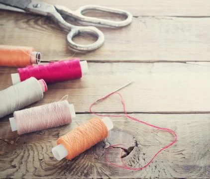 Scissors, bobbins with thread and needles. Old sewing tools on the old wooden Stock Photos