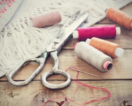 Scissors, bobbins with thread and needles, striped fabric. Old sewing tools o Stock Photos