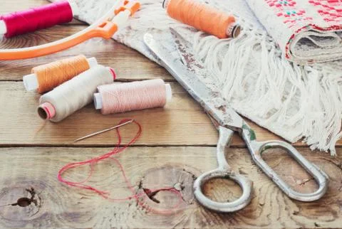 Scissors, bobbins with thread and needles, striped fabric. Old sewing tools o Stock Photos