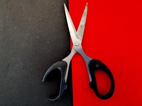 Scissors with a broken black handle on red background Stock Photos