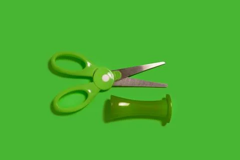Scissors with a cap on a green background Stock Photos