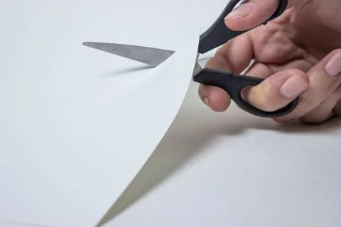 Scissors cut through the white paper. Stock Photos