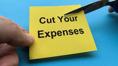 Scissors that cut yellow notepad with cut your expenses text Stock Photos