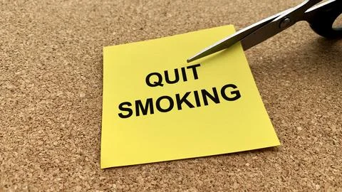 Scissors that cut yellow notepad with quit smoking text on wooden table bac.. Stock Photos