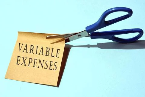 Scissors that cut yellow notepad with variable expenses text Stock-Fotos