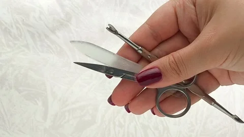 Scissors, a cuticle remover, a nail file in a young womans hand. Tools for home Stock Footage 317091612
