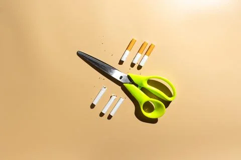 Scissors cutting cigarettes on beige backround Stock Photos