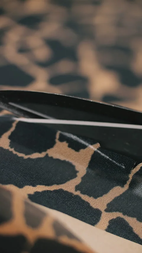 Scissors cutting giraffe patterned textile closeup Stock Footage 309006076