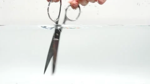 Scissors cutting through water isolated and white and slow motion Video stock 219520900