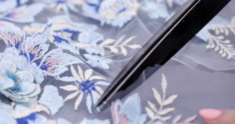 Scissors cutting transparent fabric on the ceiling patterns of colored flowers Stock Footage 237328917