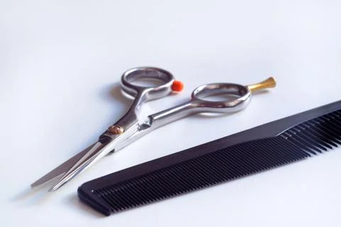 Scissors with finger rest on ring and comb isolated on white background. Stock Photos