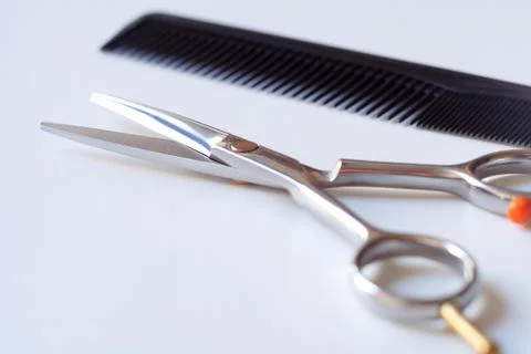 Scissors with finger rest on ring and comb isolated on white background. Stock Photos
