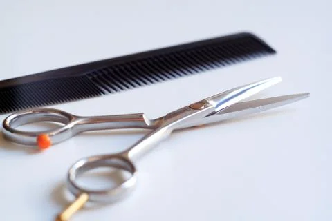 Scissors with finger rest on ring and comb isolated on white background. 库存照片